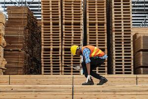 africano trabajadores hombre Ingenieria caminando y inspeccionando con trabajando suite vestir y mano guante en madera madera depósito. concepto de inteligente industria trabajador operando. madera suerte Produce madera paladar. foto