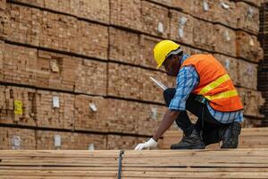 africano trabajadores hombre Ingenieria caminando y inspeccionando con trabajando suite vestir y mano guante en madera madera depósito. concepto de inteligente industria trabajador operando. madera suerte Produce madera paladar. foto