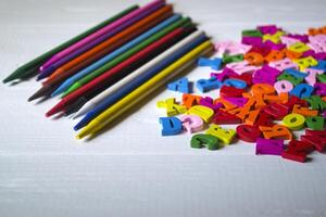 Multicolor letters and set of pencils on the table. Colorful wooden alphabet and pencils on a table. photo