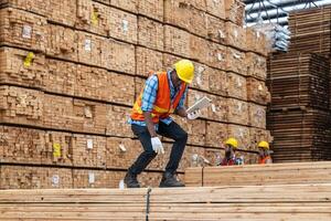 africano trabajadores hombre Ingenieria caminando y inspeccionando con trabajando suite vestir y mano guante en madera madera depósito. concepto de inteligente industria trabajador operando. madera suerte Produce madera paladar. foto