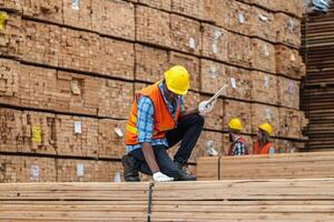 African workers man engineering walking and inspecting with working suite dress and hand glove in timber wood warehouse. Concept of smart industry worker operating. Wood factories produce wood palate. photo