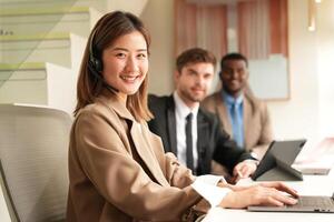 Asian operator working in office. Young friendly operator woman agent with headsets working in a call centre. photo
