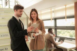 business people lady and caucasian smart man with smart tablet and talk presentation at indoor stairs way. team of business people walk in rush hour at indoor pedestrian stairs and talk together. photo