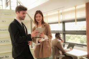 business people lady and caucasian smart man with smart tablet and talk presentation at indoor stairs way. team of business people walk in rush hour at indoor pedestrian stairs and talk together. photo