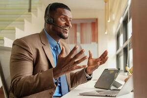 Customer Support Call Center Operator Or Receptionist. customer service and man consultant talking while doing a consultation online. African operator male telemarketing agent on a laptop in office photo