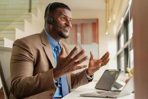 Customer Support Call Center Operator Or Receptionist. customer service and man consultant talking while doing a consultation online. African operator male telemarketing agent on a laptop in office photo