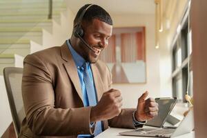 Customer Support Call Center Operator Or Receptionist. customer service and man consultant talking while doing a consultation online. African operator male telemarketing agent on a laptop in office photo