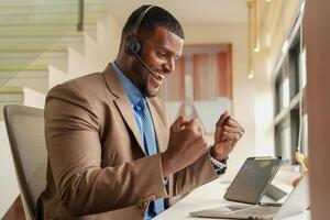 Customer Support Call Center Operator Or Receptionist. customer service and man consultant talking while doing a consultation online. African operator male telemarketing agent on a laptop in office photo