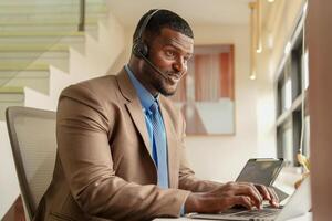 Customer Support Call Center Operator Or Receptionist. customer service and man consultant talking while doing a consultation online. African operator male telemarketing agent on a laptop in office photo