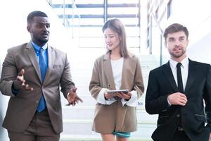 Business people shaking hands. finishing up a meeting. team of business people walk in rush hour at indoor pedestrian stairs and talk together. concept negotiations in feeling successful and happy. photo