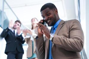 Smart black businessman watching mobile phone. Bald adult man wearing formal wear. Thoughtful African-American Businessman in a Perfectly Tailored Suit Standing in Stairway in office. photo