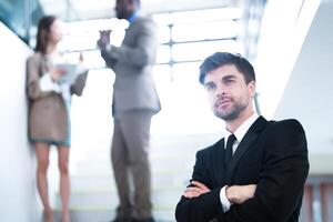 business people and office concept. happy smiling businessman in dark suit. Portrait of smiling mid adult businessman standing at corporate office. Businessman smiling with arms crossed in office. photo