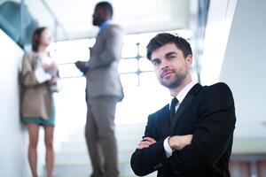 business people and office concept. happy smiling businessman in dark suit. Portrait of smiling mid adult businessman standing at corporate office. Businessman smiling with arms crossed in office. photo