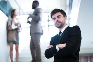 business people and office concept. happy smiling businessman in dark suit. Portrait of smiling mid adult businessman standing at corporate office. Businessman smiling with arms crossed in office. photo