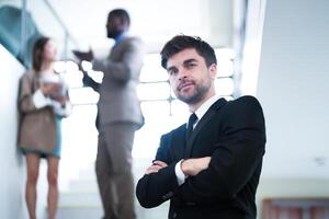 business people and office concept. happy smiling businessman in dark suit. Portrait of smiling mid adult businessman standing at corporate office. Businessman smiling with arms crossed in office. photo