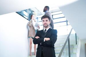 business people and office concept. happy smiling businessman in dark suit. Portrait of smiling mid adult businessman standing at corporate office. Businessman smiling with arms crossed in office. photo