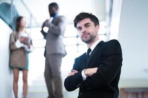 business people and office concept. happy smiling businessman in dark suit. Portrait of smiling mid adult businessman standing at corporate office. Businessman smiling with arms crossed in office. photo