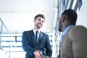 Business people shaking hands. finishing up a meeting. team of business people walk in rush hour at indoor pedestrian stairs and talk together. concept negotiations in feeling successful and happy. photo