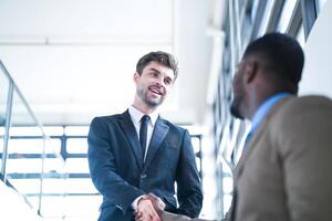 Business people shaking hands. finishing up a meeting. team of business people walk in rush hour at indoor pedestrian stairs and talk together. concept negotiations in feeling successful and happy. photo