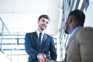 Business people shaking hands. finishing up a meeting. team of business people walk in rush hour at indoor pedestrian stairs and talk together. concept negotiations in feeling successful and happy. photo