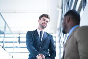 Business people shaking hands. finishing up a meeting. team of business people walk in rush hour at indoor pedestrian stairs and talk together. concept negotiations in feeling successful and happy. photo