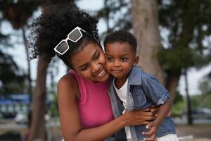 Mixed race African and Asian mother and boy is playing at the outdoor area. smiling happy family have fun running on the beach. portrait of mom and kid lifestyle with a unique hairstyle. photo