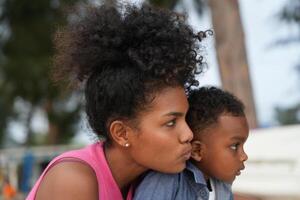 Mixed race African and Asian mother and boy is playing at the outdoor area. smiling happy family have fun running on the beach. portrait of mom and kid lifestyle with a unique hairstyle. photo