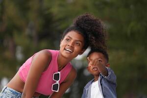 Mixed race African and Asian mother and boy is playing at the outdoor area. smiling happy family have fun running on the beach. portrait of mom and kid lifestyle with a unique hairstyle. photo