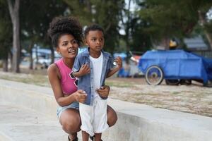 Mixed race African and Asian mother and boy is playing at the outdoor area. smiling happy family have fun running on the beach. portrait of mom and kid lifestyle with a unique hairstyle. photo