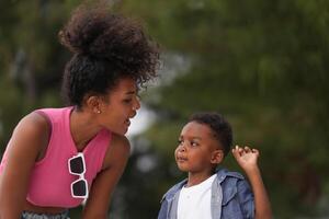Mixed race African and Asian mother and boy is playing at the outdoor area. smiling happy family have fun running on the beach. portrait of mom and kid lifestyle with a unique hairstyle. photo