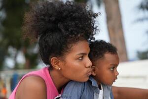 Mixed race African and Asian mother and boy is playing at the outdoor area. smiling happy family have fun running on the beach. portrait of mom and kid lifestyle with a unique hairstyle. photo