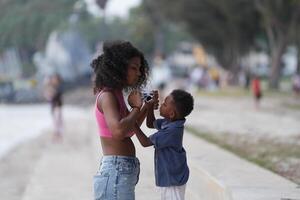 Mixed race African and Asian mother and boy is playing at the outdoor area. smiling happy family have fun running on the beach. portrait of mom and kid lifestyle with a unique hairstyle. photo