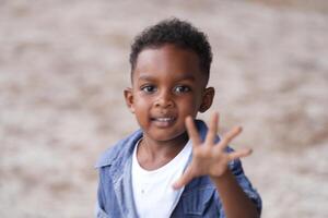 Mixed race African and Asian boy is playing at the outdoor area. smiling happy boy has fun running on the beach. portrait of boy lifestyle with a unique hairstyle. photo