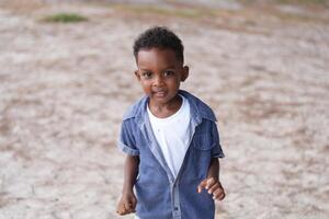 Mixed race African and Asian boy is playing at the outdoor area. smiling happy boy has fun running on the beach. portrait of boy lifestyle with a unique hairstyle. photo