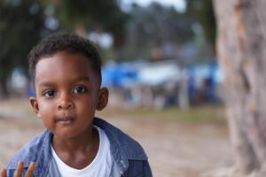 Mixed race African and Asian boy is playing at the outdoor area. smiling happy boy has fun running on the beach. portrait of boy lifestyle with a unique hairstyle. photo