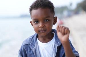 Mixed race African and Asian boy is playing at the outdoor area. smiling happy boy has fun running on the beach. portrait of boy lifestyle with a unique hairstyle. photo