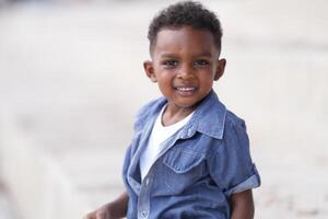 mezclado carrera africano y asiático chico es jugando a el al aire libre área. sonriente contento chico tiene divertido corriendo en el playa. retrato de chico estilo de vida con un único peinado. foto