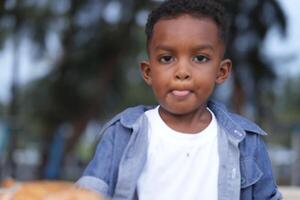 Mixed race African and Asian boy is playing at the outdoor area. smiling happy boy has fun running on the beach. portrait of boy lifestyle with a unique hairstyle. photo