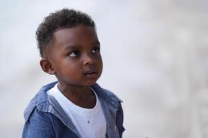 Mixed race African and Asian boy is playing at the outdoor area. smiling happy boy has fun running on the beach. portrait of boy lifestyle with a unique hairstyle. photo