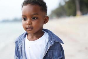 Mixed race African and Asian boy is playing at the outdoor area. smiling happy boy has fun running on the beach. portrait of boy lifestyle with a unique hairstyle. photo