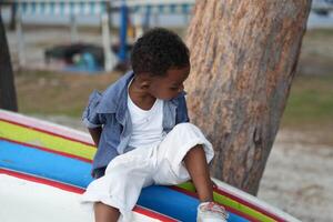 Mixed race African and Asian boy is playing at the outdoor area. smiling happy boy has fun running on the beach. portrait of boy lifestyle with a unique hairstyle. photo