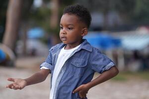 Mixed race African and Asian boy is playing at the outdoor area. smiling happy boy has fun running on the beach. portrait of boy lifestyle with a unique hairstyle. photo