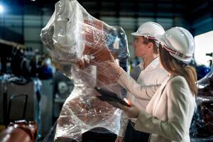 Sales manager and factory owner in suits negotiating selling robots used in the factory. Business engineers meeting and checking new machine robot. Workers walking at warehouse welding machine. photo