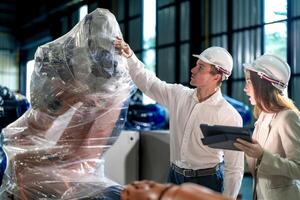 Sales manager and factory owner in suits negotiating selling robots used in the factory. Business engineers meeting and checking new machine robot. Workers walking at warehouse welding machine. photo