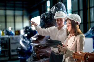 Business engineers meeting and checking new machine robot. Workers walking at warehouse industry welding machine. business negotiation concepts and technology. women Using smart Tablet to present man. photo