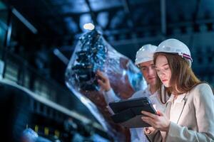 Business engineers meeting and checking new machine robot. Workers walking at warehouse industry welding machine. business negotiation concepts and technology. women Using smart Tablet to present man. photo