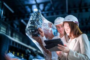 negocio ingenieros reunión y comprobación nuevo máquina robot. trabajadores caminando a almacén industria soldadura máquina. negocio negociación conceptos y tecnología. mujer utilizando inteligente tableta a presente hombre. foto