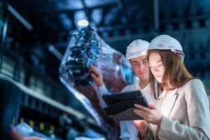 Business engineers meeting and checking new machine robot. Workers walking at warehouse industry welding machine. business negotiation concepts and technology. women Using smart Tablet to present man. photo