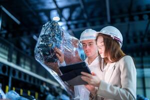 Sales manager and factory owner in suits negotiating selling robots used in the factory. Business engineers meeting and checking new machine robot. Workers walking at warehouse welding machine. photo