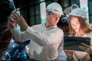 Sales manager and factory owner in suits negotiating selling robots used in the factory. Business engineers meeting and checking new machine robot. Workers walking at warehouse welding machine. photo